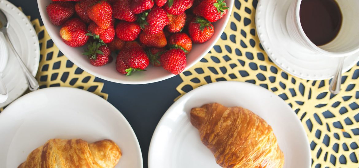 bowl of strawberries and croissants on a kitchen table