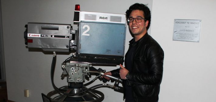 Rowan RTF Student Frank Villarreal poses next to the antique canon camera