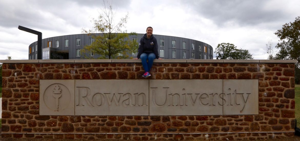 Jereca sitting on Rowan University brick sign outside of Holly Pointe