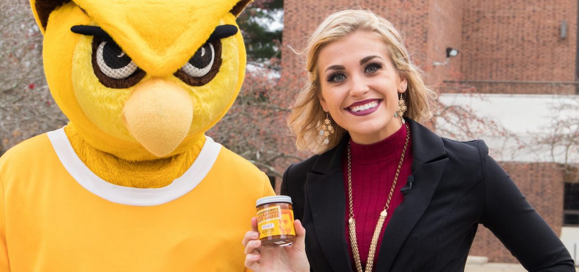Rowan student stands next to the prof holding hot sauce