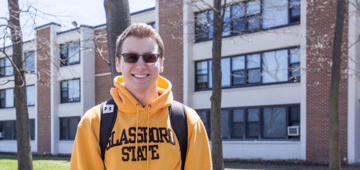 Scott Timko is a resident assistant in Mullica Hall, wearing a yellow sweatshirt that says Glassboro State