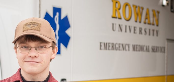 Young man standing in front of a white and yellow Rowan EMS vehicle