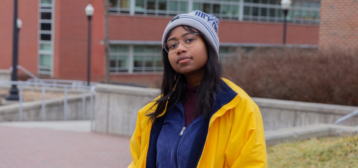 A student wearing a beanie, yellow jacket and blue sweater