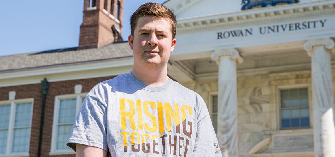 Jason, wearing a Rising Rowan shirt, standing outside Bunce Hall