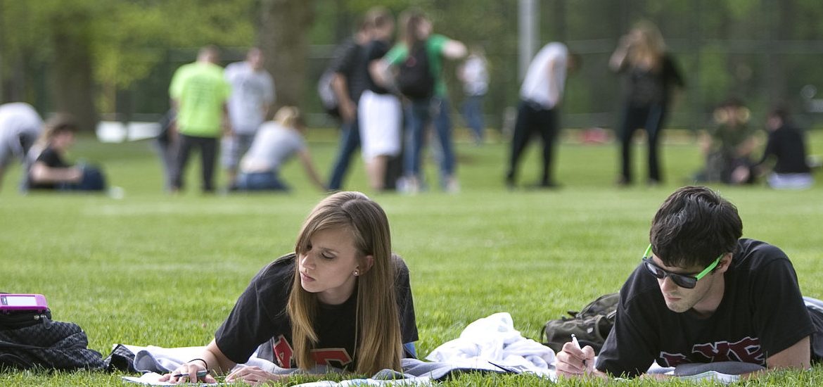 Students studying and playing on a field