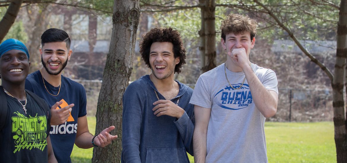 A candid photo of four male freshmen laughing together.