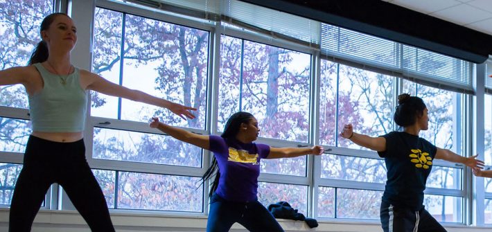 students dancing in a bright room with windows.