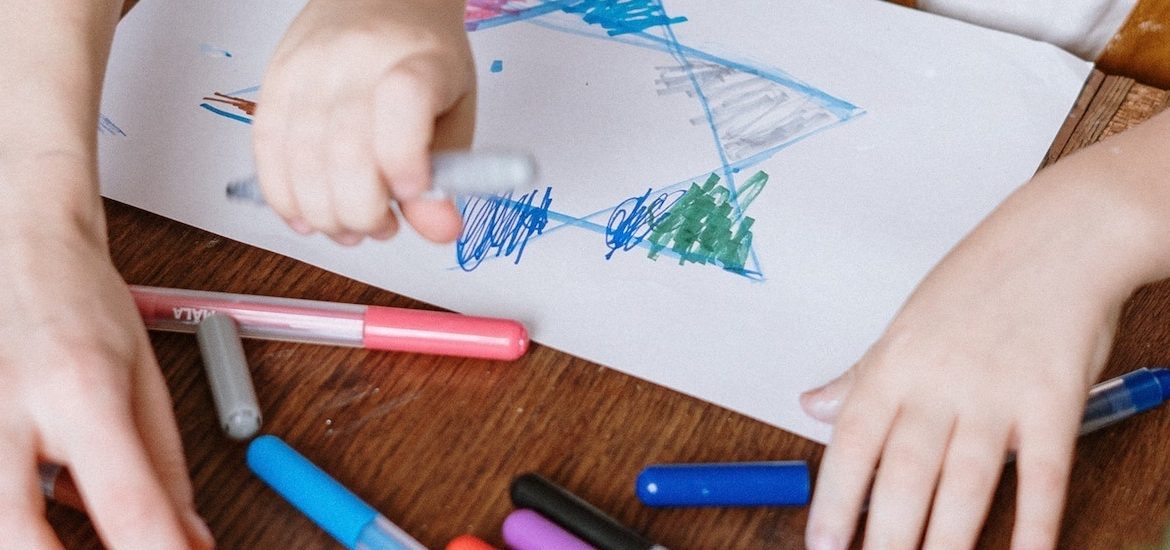 Stock image of close up of adult hands guiding child's hands drawing.