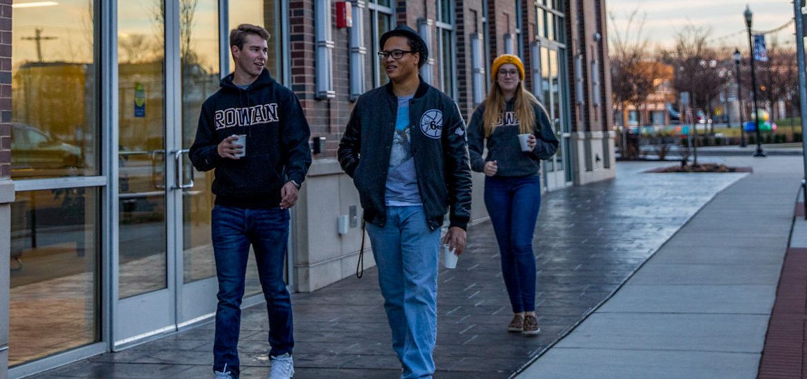 Christian walks down Rowan Boulevard with two other students