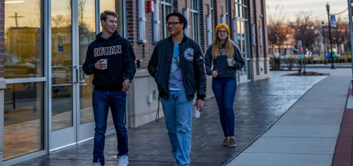 Christian walks down Rowan Boulevard with two other students