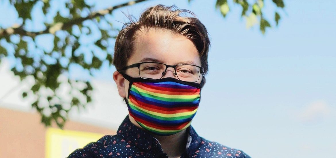 Emerson wears a rainbow mask outside.
