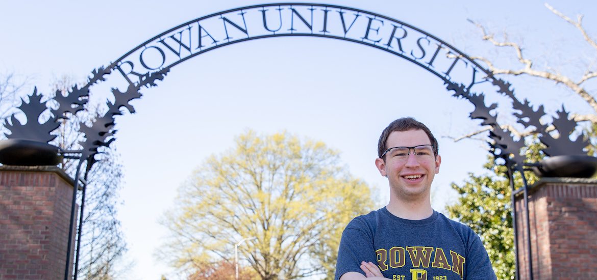Kevin stands in front of the Rowan arch in a Rowan t-shirt.