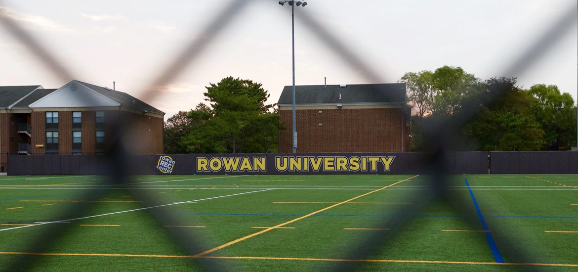 An athletic field as seen through a fence on campus.