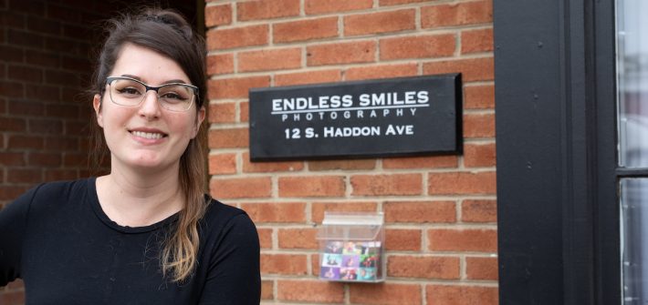 Gabi stands in front of the Endless Smiles Photography Sign