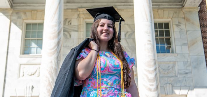Kassidy stands in front of Bunce Hall with her cap and gown.