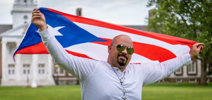 Brandon holding the Dominican Republic flag in front of Bunce hall.