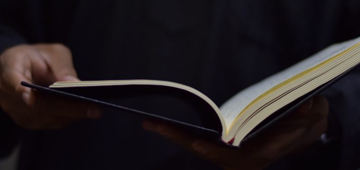 Stock image of a person's hands holding a hardcover book.