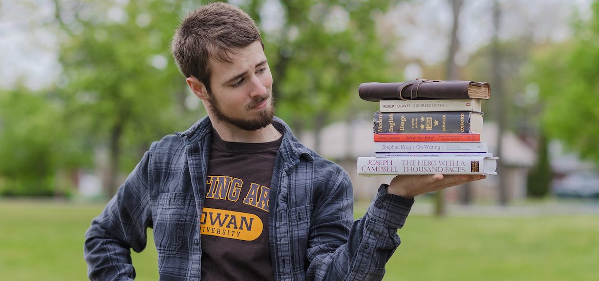 Eric Uhorchuk holds a stack of Writing Arts materials outside on campus.