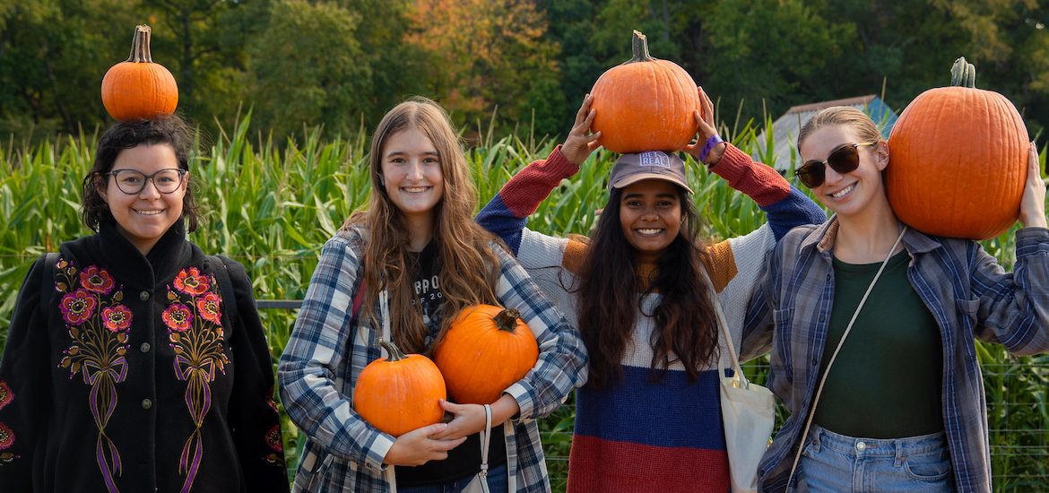 Rowan University students smile with pumpkins they found at nearby Creamy Acres Farm.