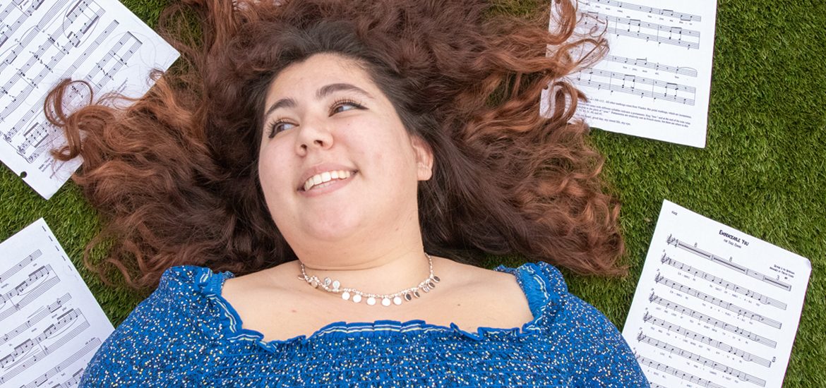 Arianna Granda lays on the grass with musical scores surrounding her.