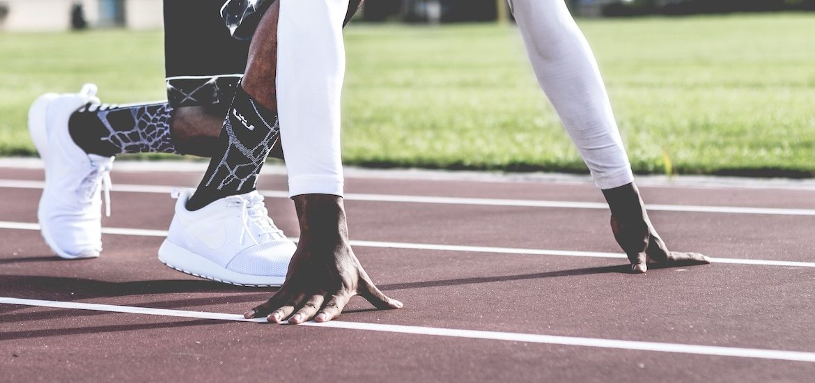 Stock image of close up of a runner's feet and hands on the track ready to run.