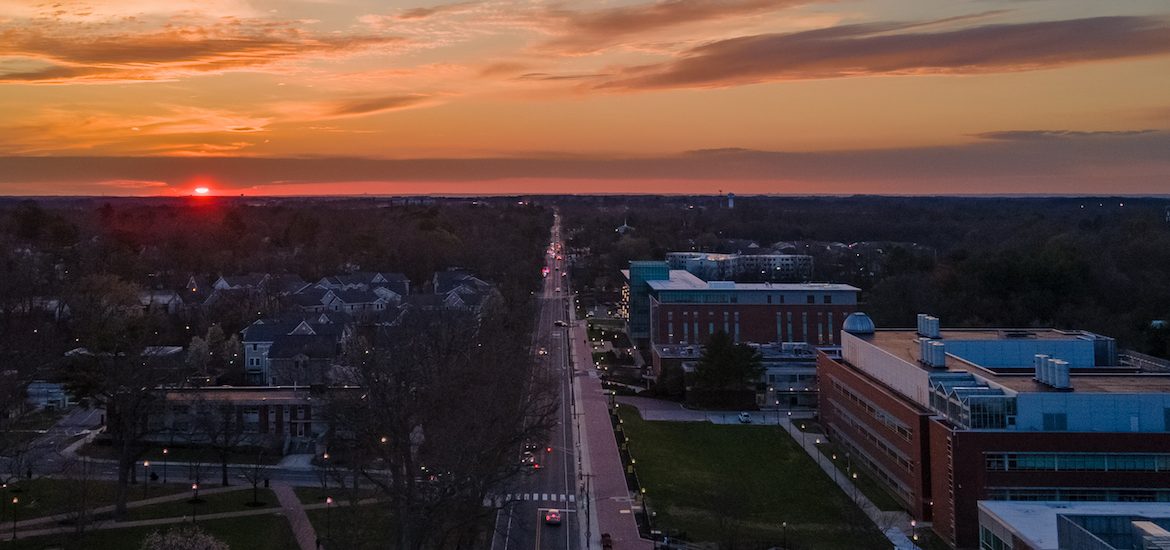 A drone shot of Glassboro, NJ, centering Rowan University, with a dramatically bright sunset behind the town.